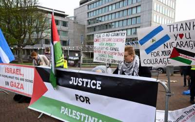 group of pro-Palestine protesters with banners outside the International Court of Justice (ICJ)