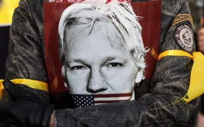 A demonstrator holds an image of Julian Assange during a protest outside of the Royal Courts of Justice in London, Britain