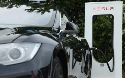 A Tesla electric-powered sedan stands at a Tesla charging staiton
