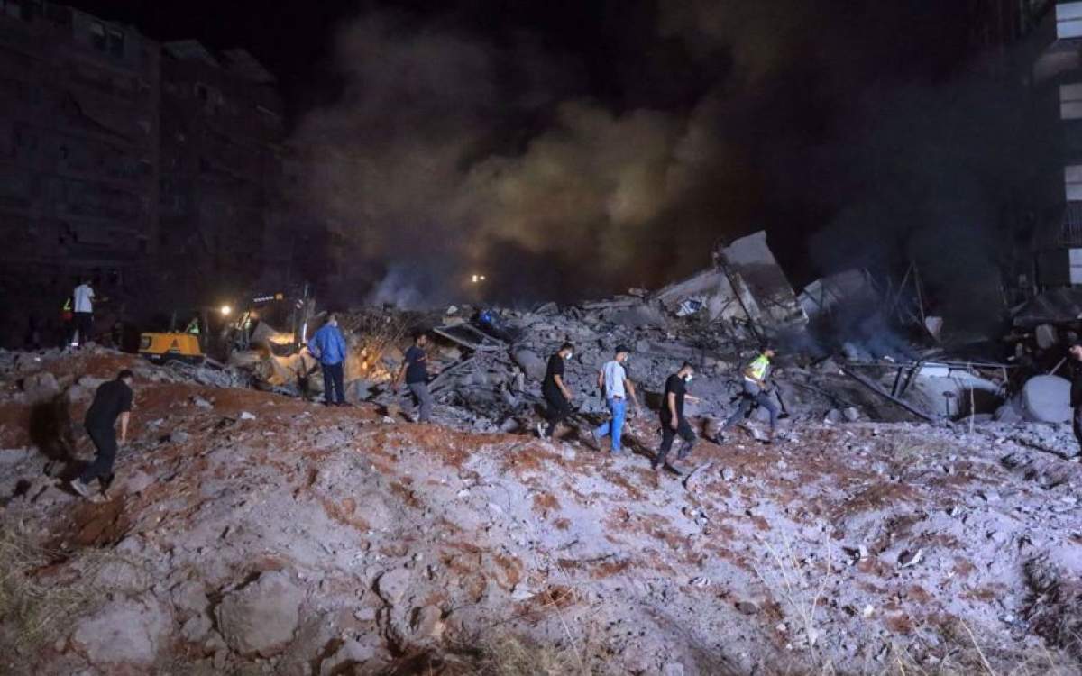 People and first responders stand on the rubble of a building destroyed in an Israeli airstrike in the Haret Hreik neighborhood of Beirut